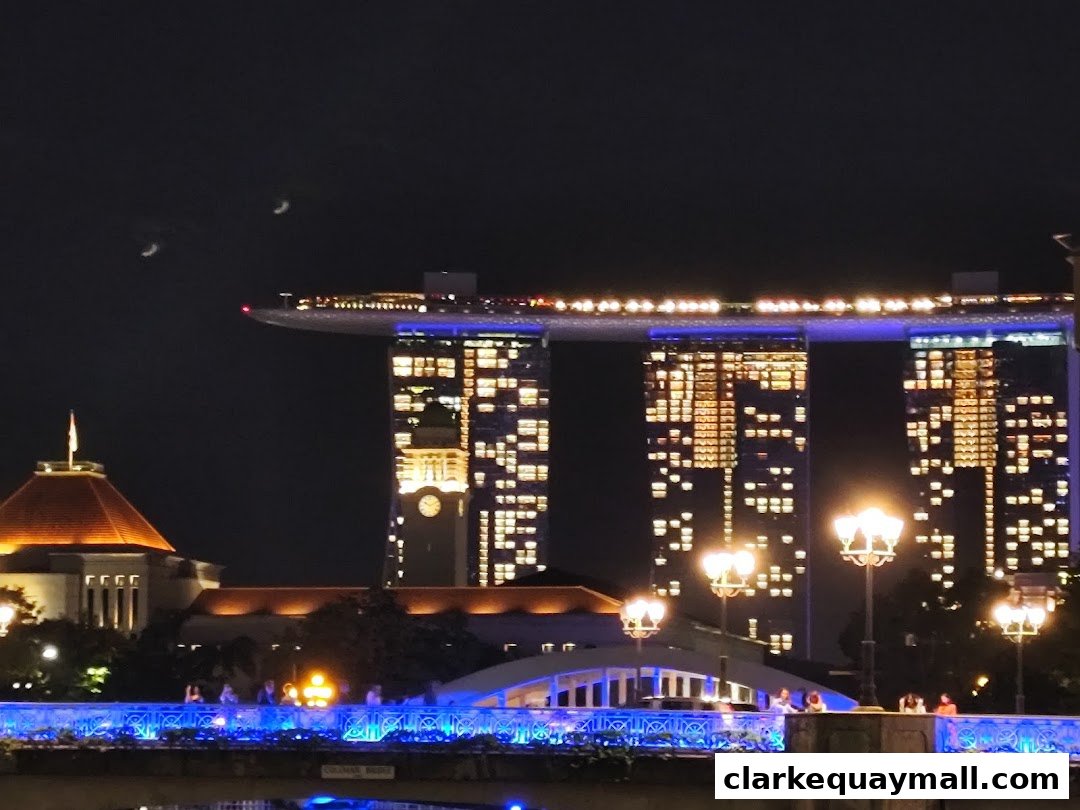 Night view of Marina Bay Sands with illuminated buildings and a bridge.