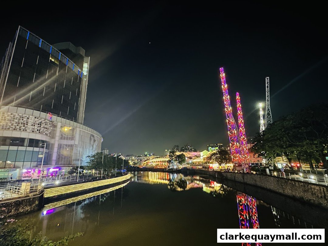 Night view of a river with illuminated buildings and amusement rides.