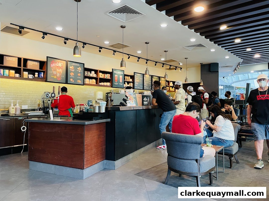 Interior view of a busy Starbucks cafe with customers ordering and seated.