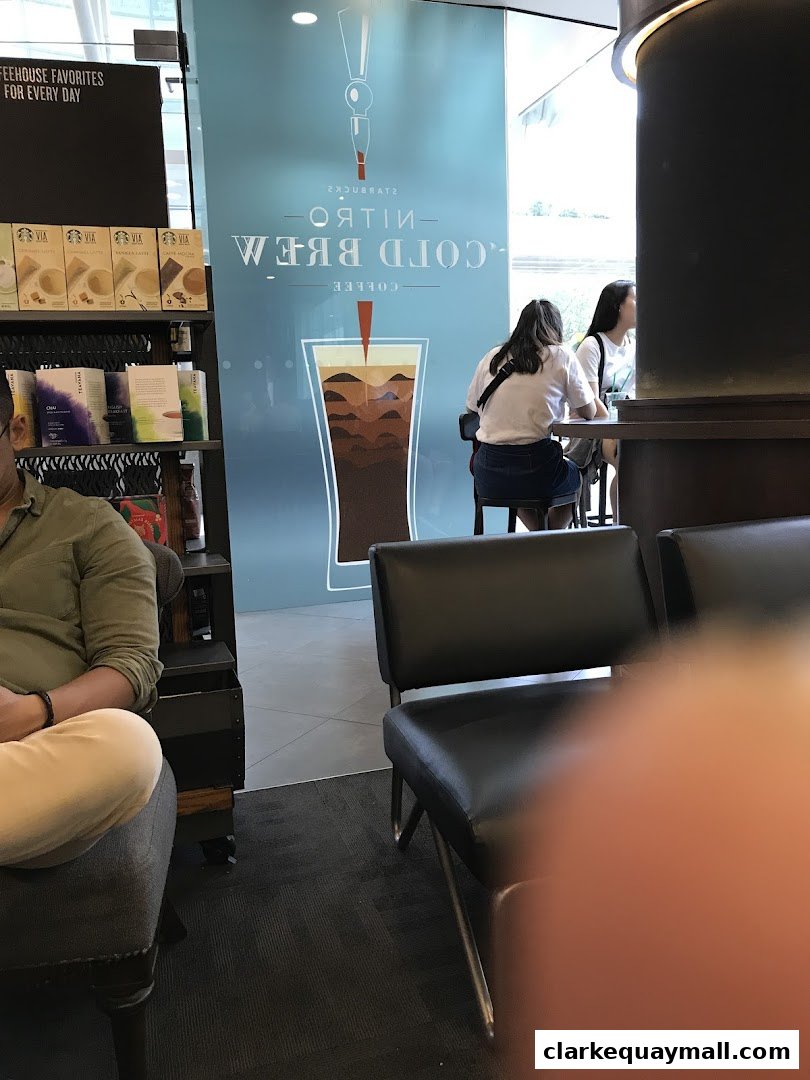 Interior shot of Starbucks with customers seated and merchandise on display.
