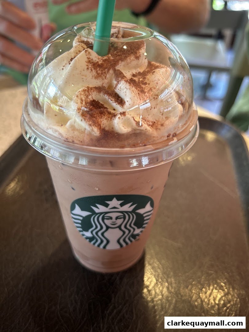 A close-up of a Starbucks iced coffee topped with whipped cream and chocolate powder.