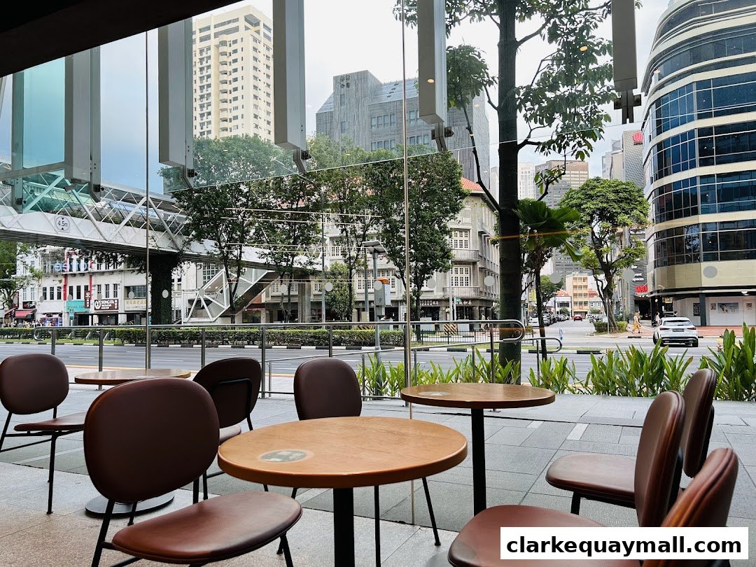 Interior view of Starbucks with tables and chairs, looking out at a city street scene.