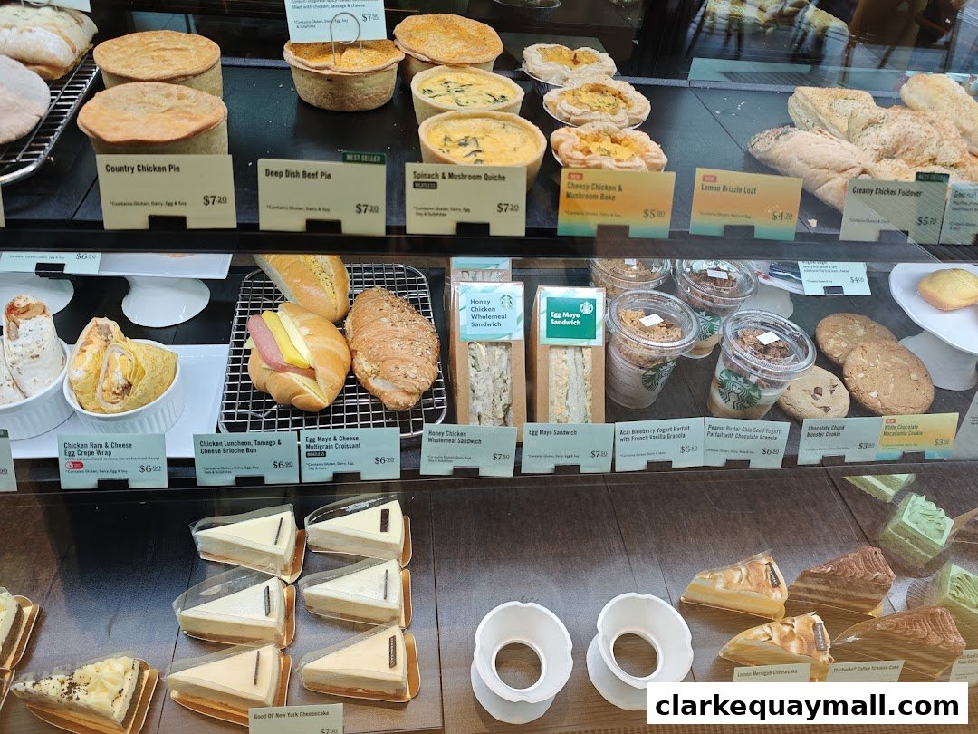 A display case filled with various pastries, sandwiches, parfaits, cookies, and cheesecakes at Starbucks.