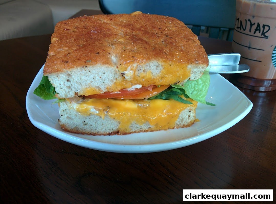 A delicious-looking sandwich with melted cheese, tomato, and lettuce on focaccia bread.