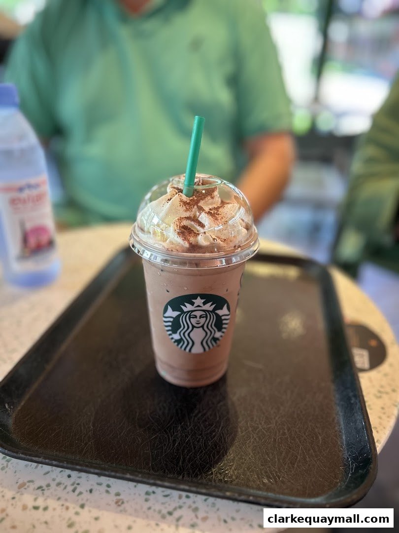 A Starbucks Frappuccino with whipped cream and chocolate powder on a tray.