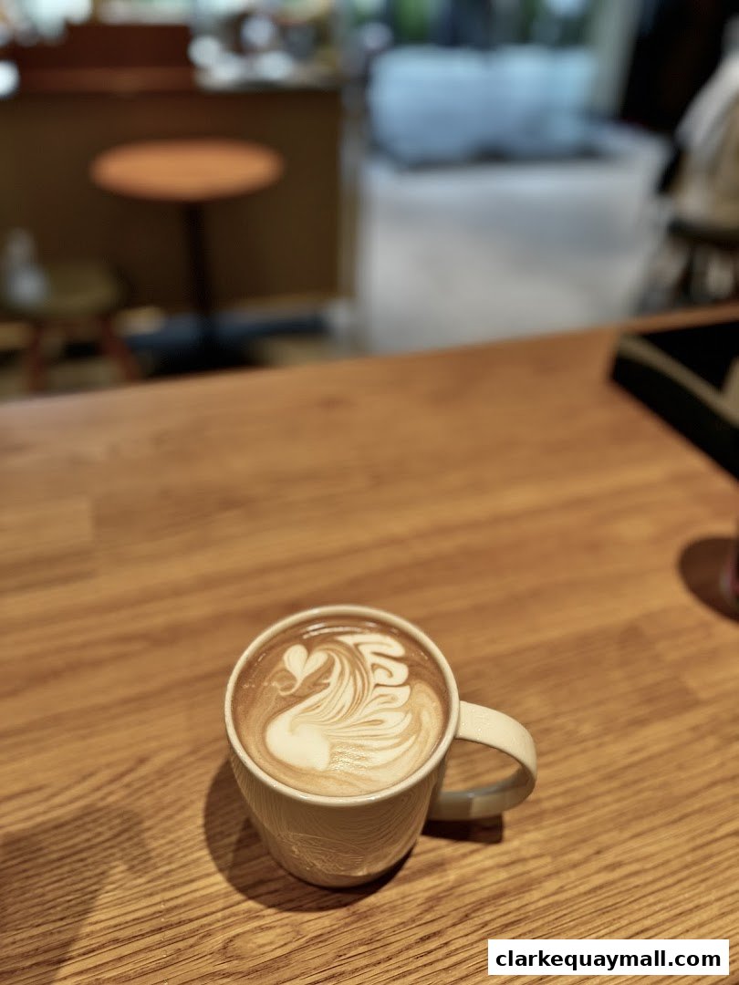 A close-up of a latte with swan art on a wooden table at Starbucks.