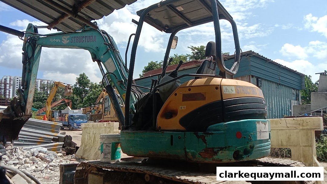 A construction site with excavators and building materials under a cloudy sky.