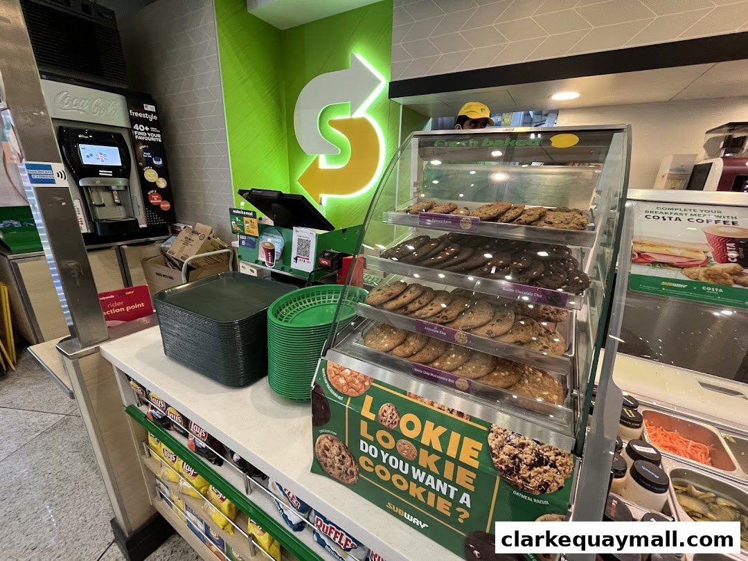 A display of freshly baked cookies and a beverage station at a Subway restaurant.