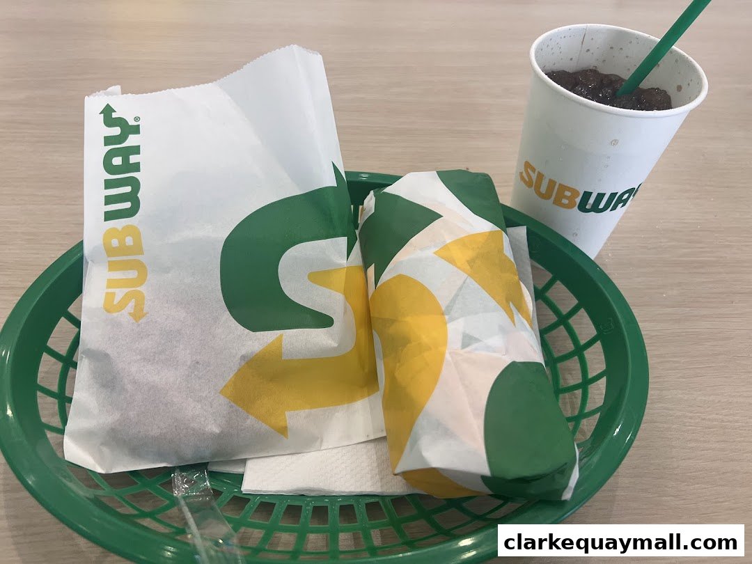 A Subway meal featuring a sandwich, a bag, and a drink in a green basket.
