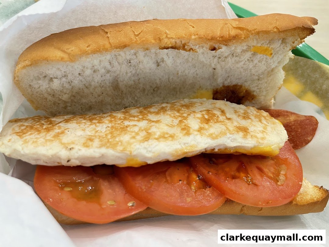 A close-up view of a Subway sandwich with fresh tomatoes, egg, and cheese on a toasted bun.