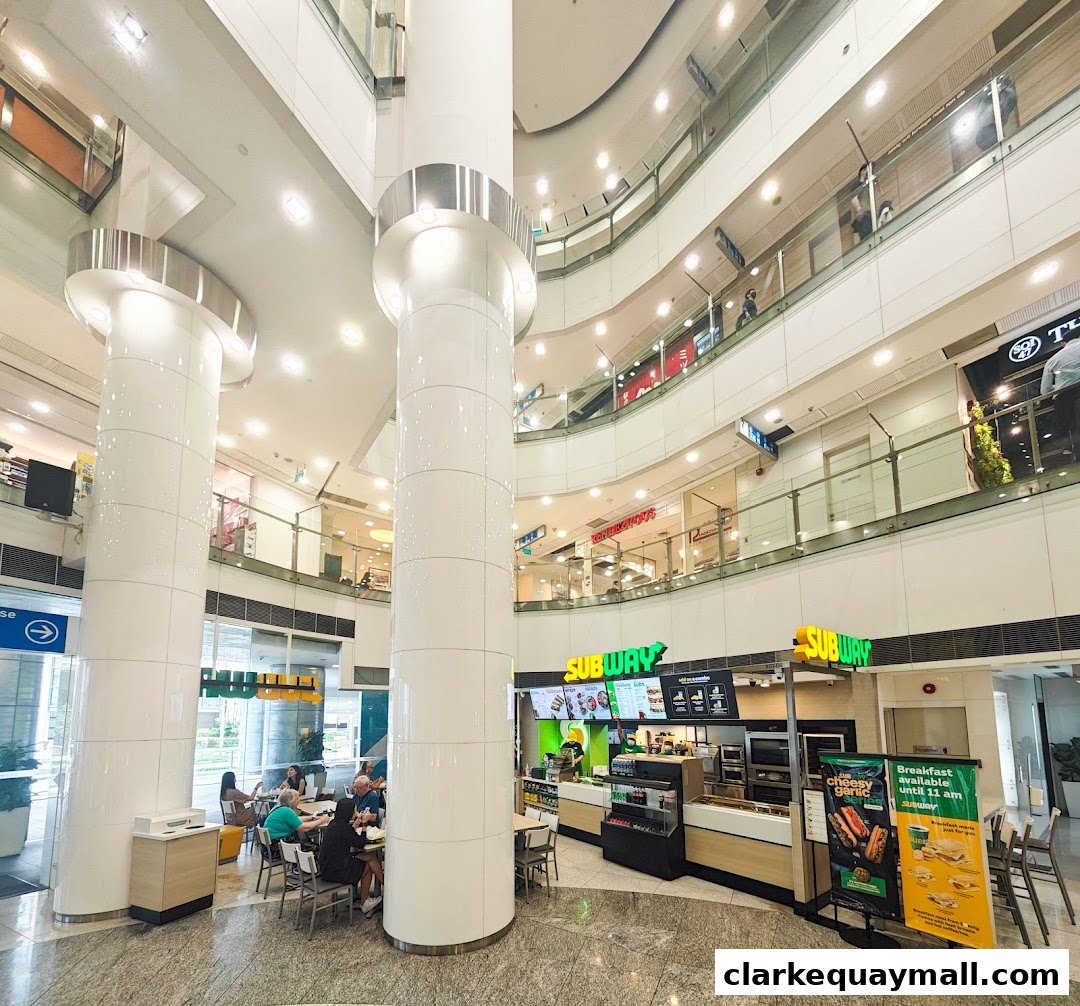 A Subway restaurant located in a multi-level shopping mall atrium with customers dining.