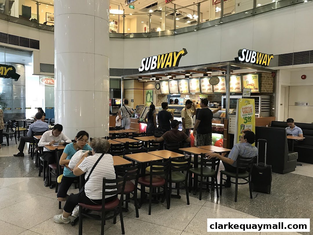 People dining at Subway restaurant with a busy interior and seating area.