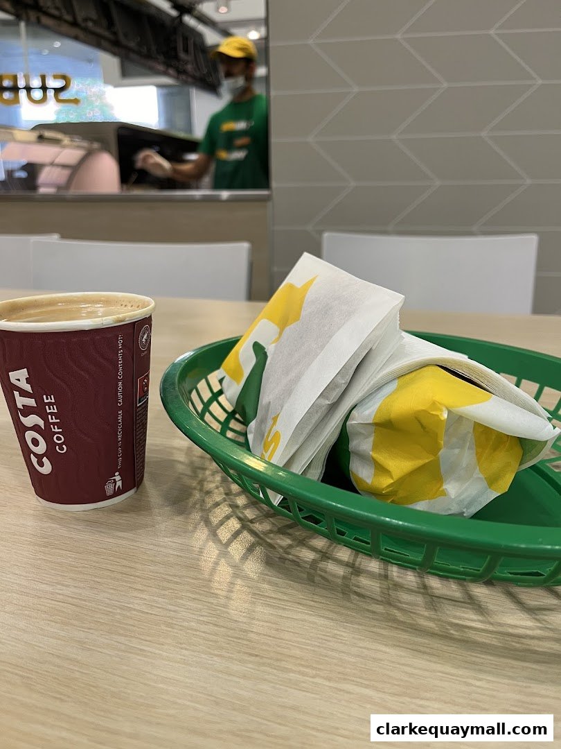 A Subway meal with sandwiches and a coffee cup on a table.