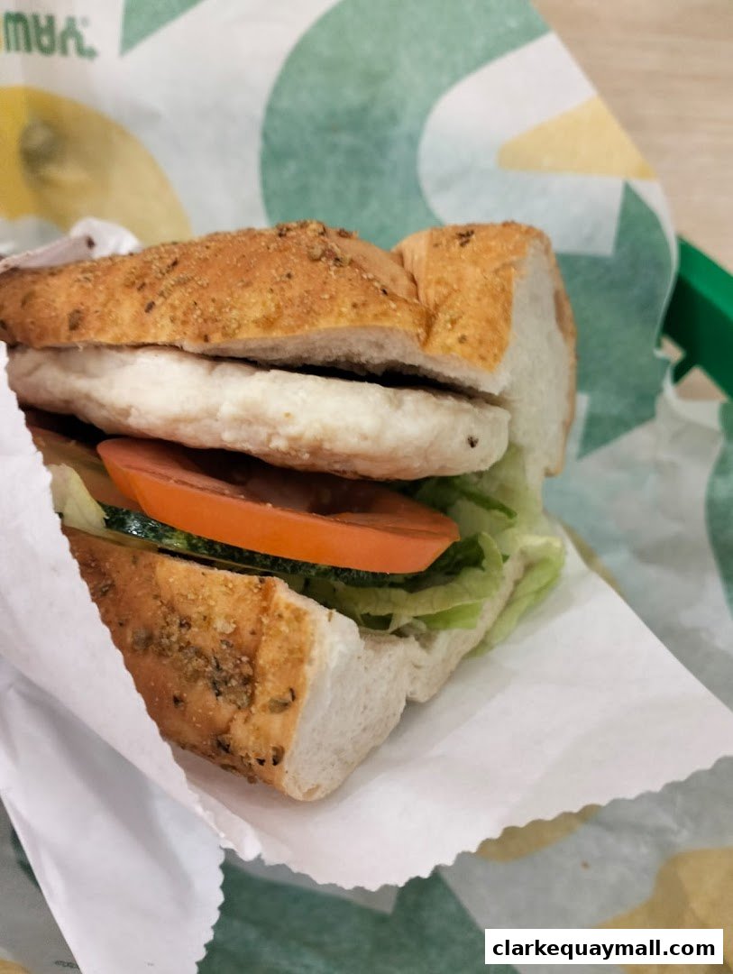 A close-up shot of a Subway sandwich with fresh lettuce, tomato, and chicken.