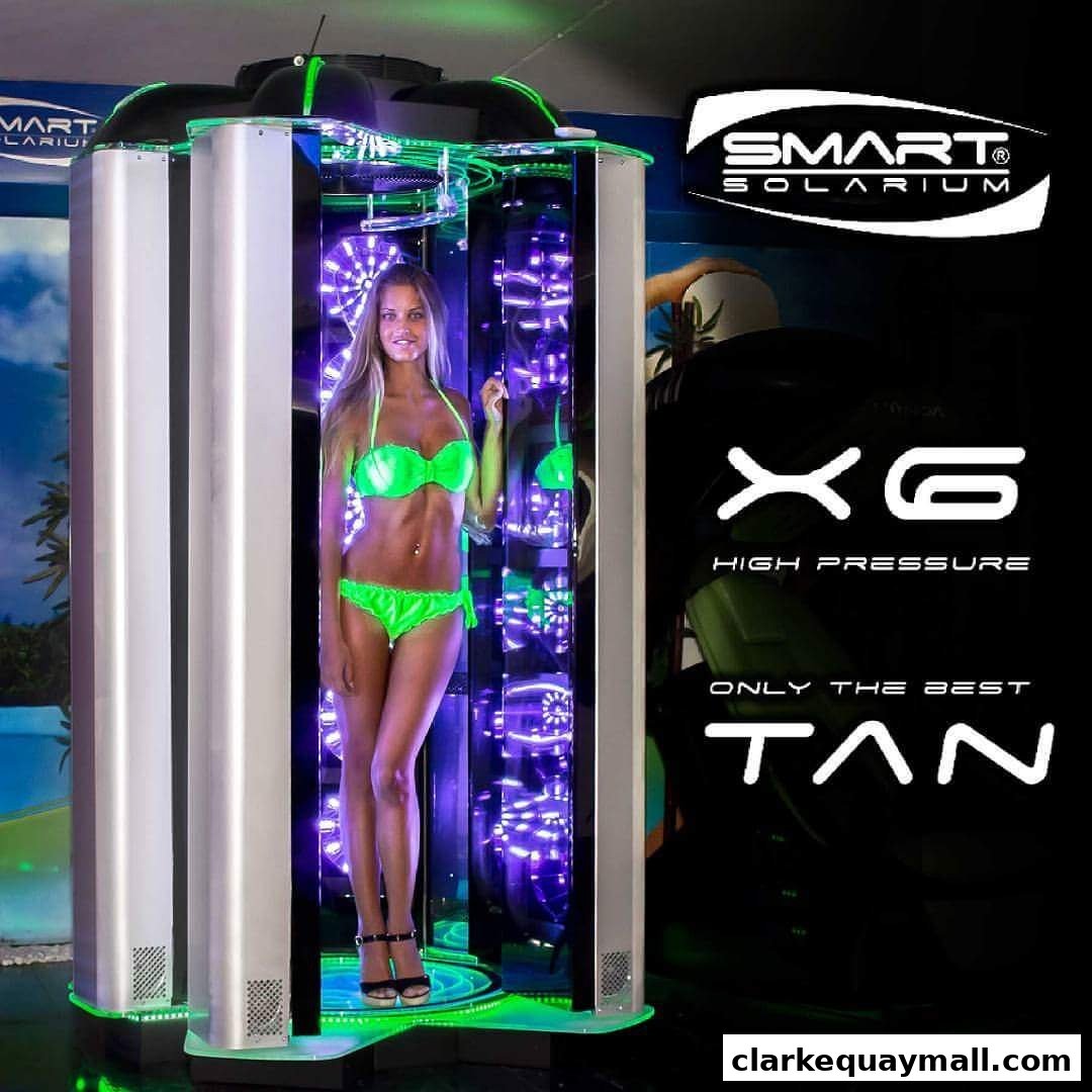 A woman in a bikini stands inside a tanning booth with purple lights.