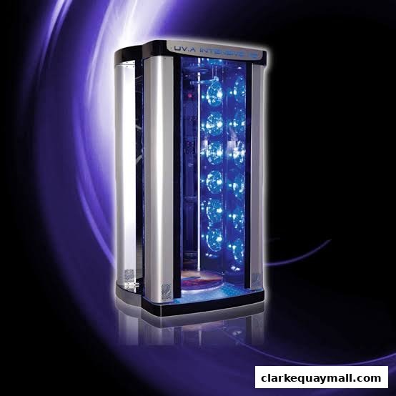 A modern, vertical tanning bed with blue UV lights and a sleek silver exterior.