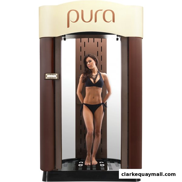 A woman in a bikini stands inside a tanning booth with the brand name 'pura' visible.