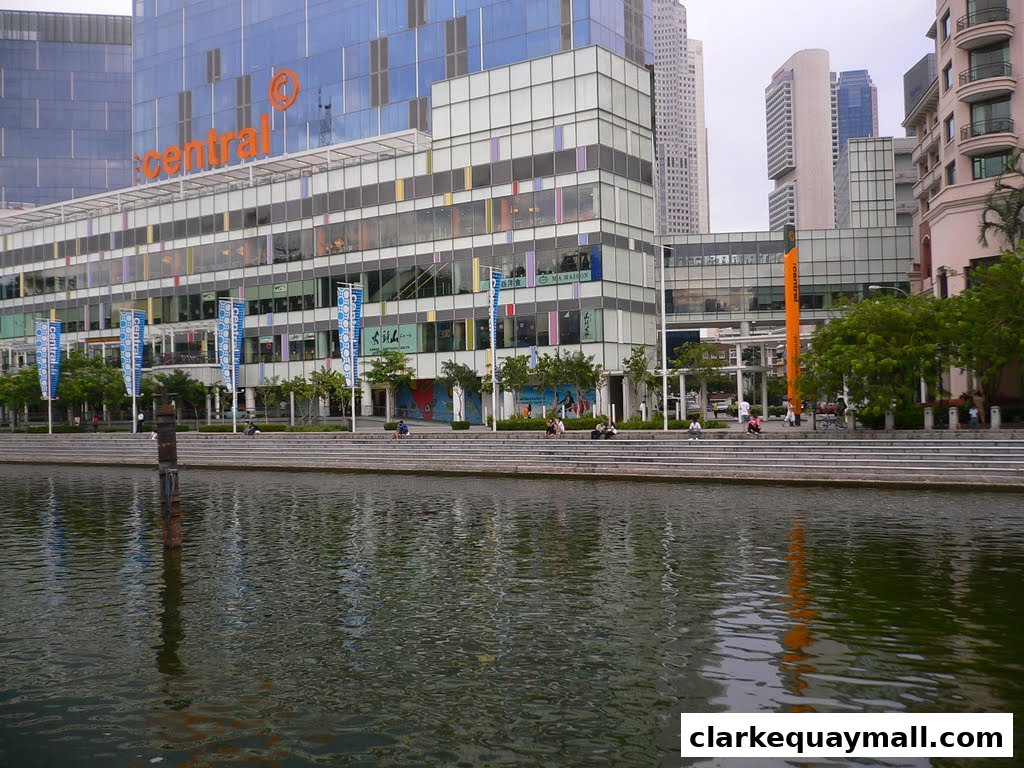 A modern building with a river in the foreground and people sitting on steps.