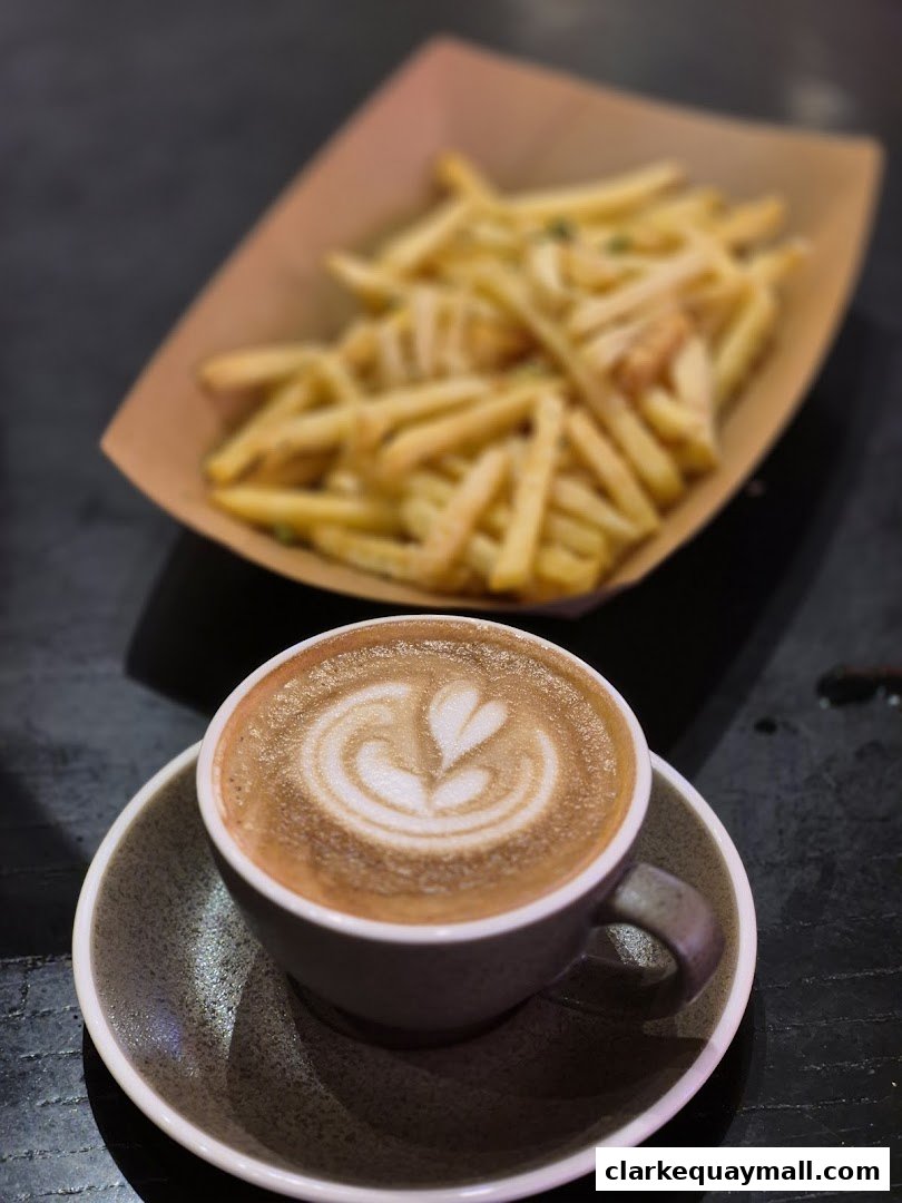 A cup of latte with latte art and a serving of french fries.