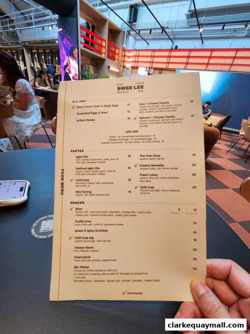 A person holds a Swee Lee Music food menu with various food and drink items listed.
