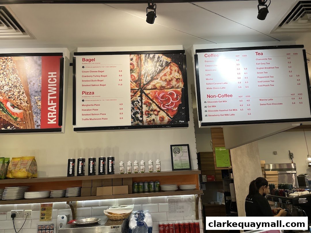A menu board displaying bagels, pizzas, coffee, tea, and non-coffee drinks at Swissbake Cafe.
