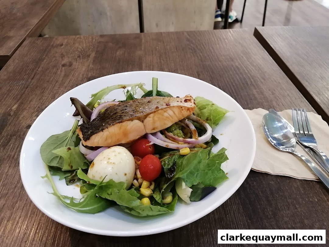 A close-up of a salmon salad with a boiled egg and cherry tomatoes on a white plate.