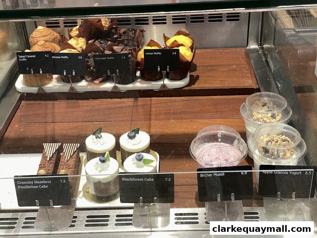 A display case filled with various pastries, cakes, and yogurts from Swissbake Cafe.