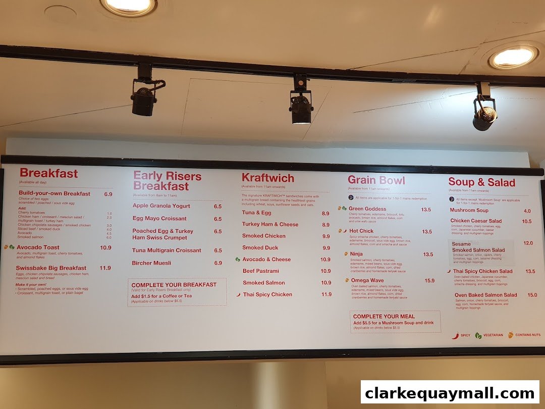A menu board displaying breakfast, sandwiches, grain bowls, and soups/salads with prices.