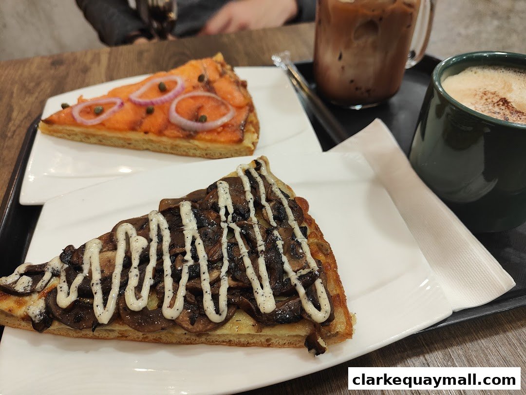 Two slices of pizza, one with salmon and onions, the other with mushrooms, and two drinks.