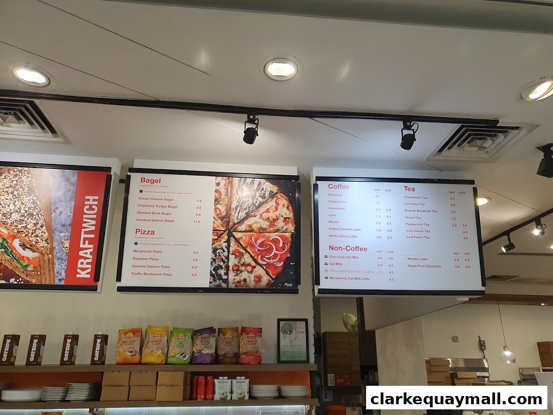 A menu board displaying bagels, pizzas, coffees, teas, and non-coffee drinks at Swissbake Cafe.