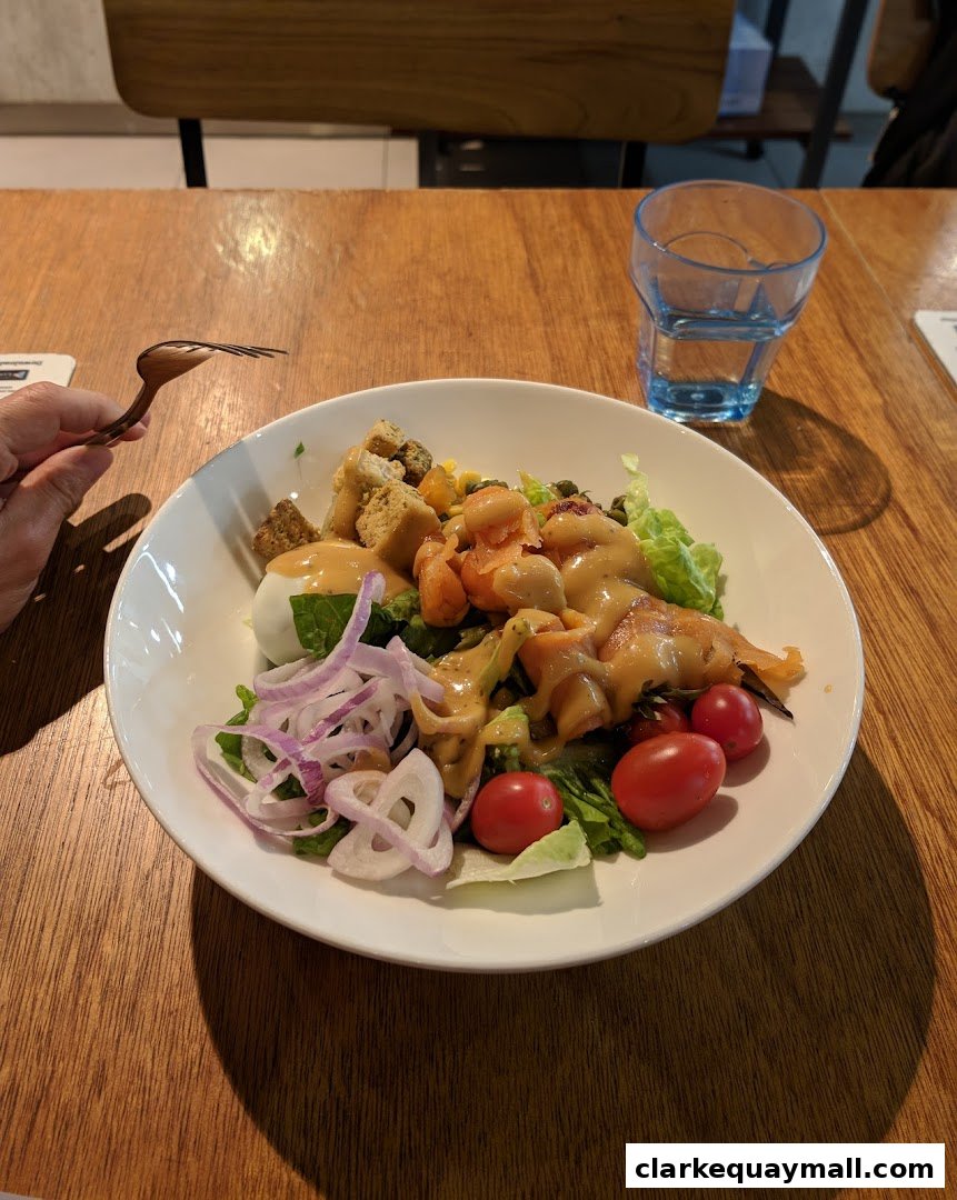 A delicious salad with salmon, egg, and vegetables, served with a glass of water.