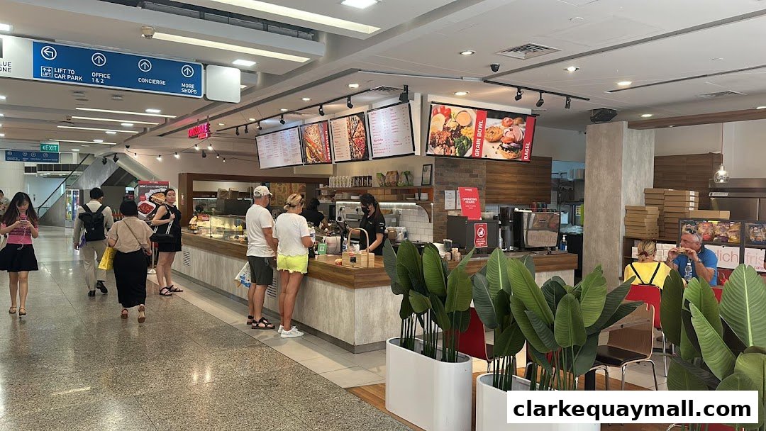 Customers ordering at a cafe counter with digital menus displaying food items.