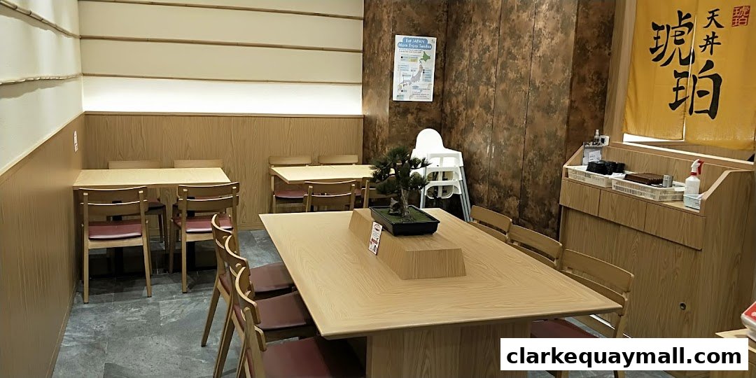 Interior of a Japanese restaurant with wooden tables, chairs, and a decorative bonsai tree.