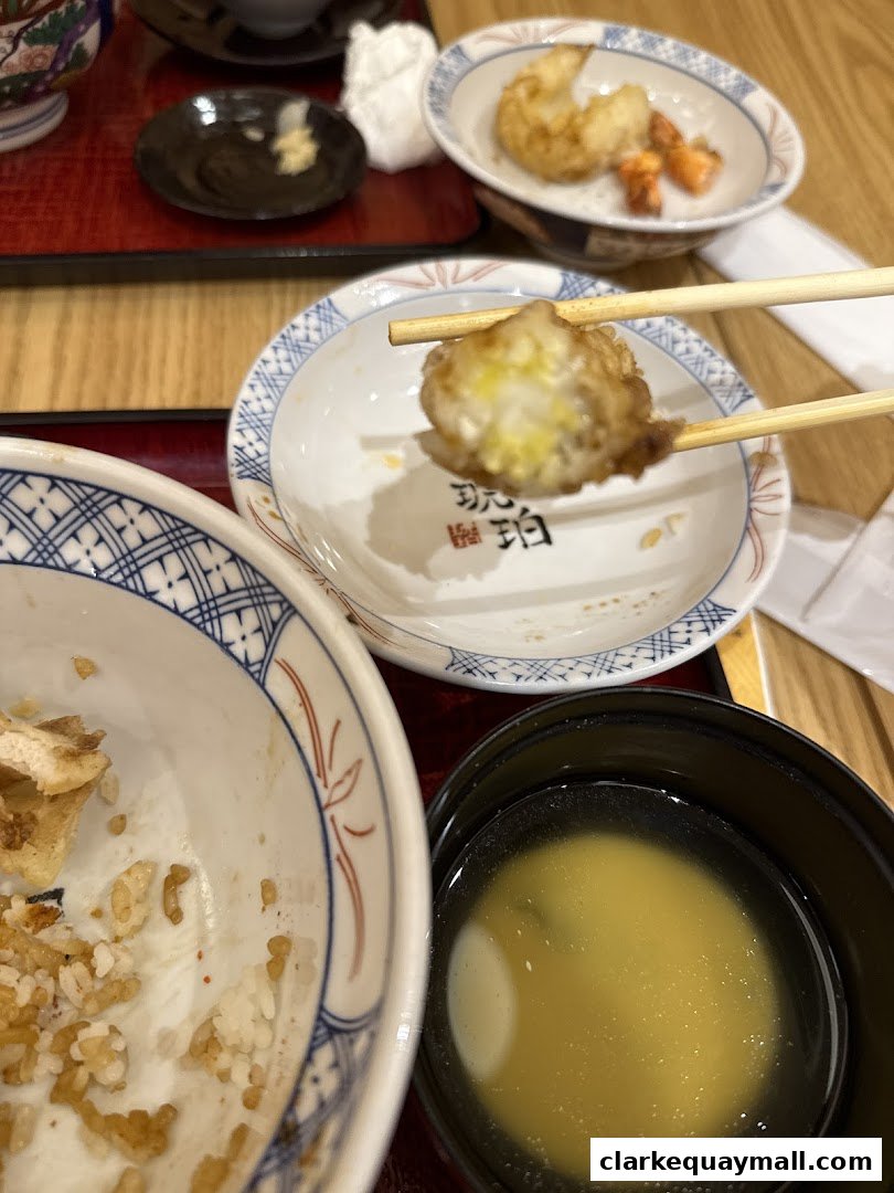 A close-up of a meal with tempura, rice, and miso soup, presented with chopsticks.