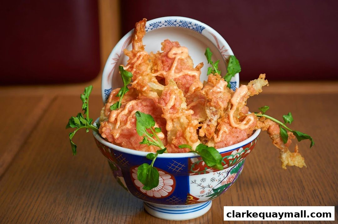 A close-up of a bowl filled with crispy tempura, drizzled with sauce and garnished with greens.
