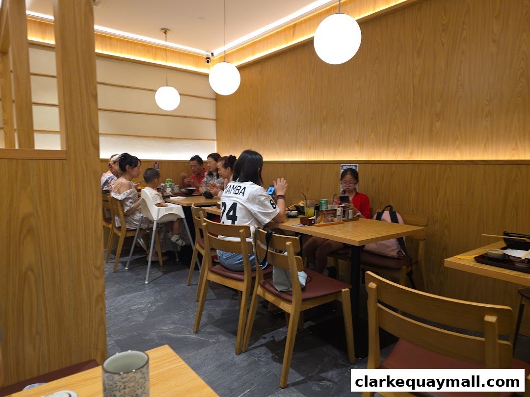 Diners enjoying a meal at tables inside a modern Japanese restaurant with wooden accents.