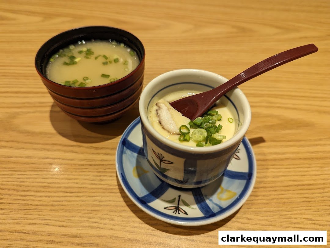 A steaming bowl of chawanmushi with a side of miso soup, garnished with green onions.