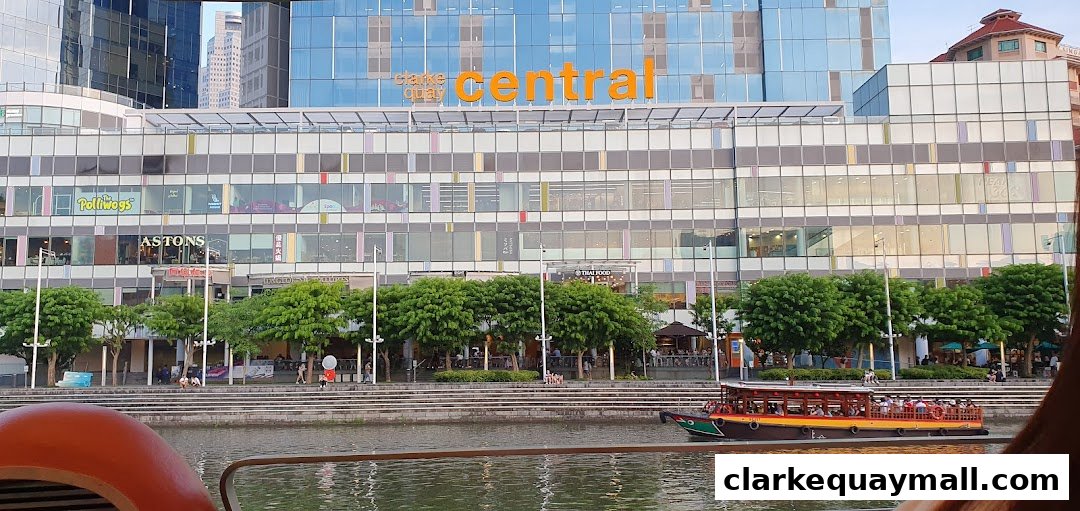 The Central shopping mall facade with shops and a riverboat on the water.
