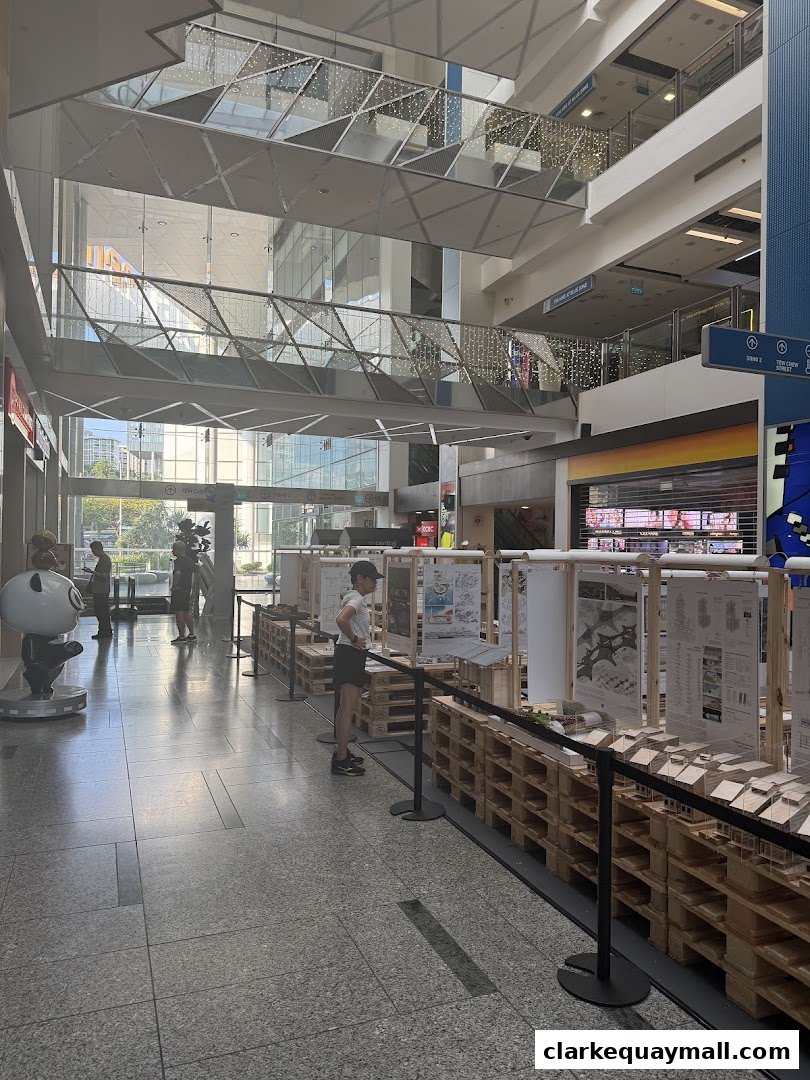 Interior view of a modern shopping mall with an exhibition display and people.