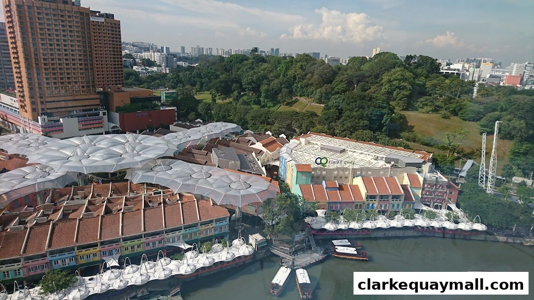 Aerial view of Clarke Quay with colorful buildings, a river, and lush greenery.