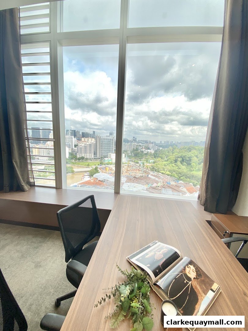 A desk with a magazine and candle overlooks a city skyline through large windows.