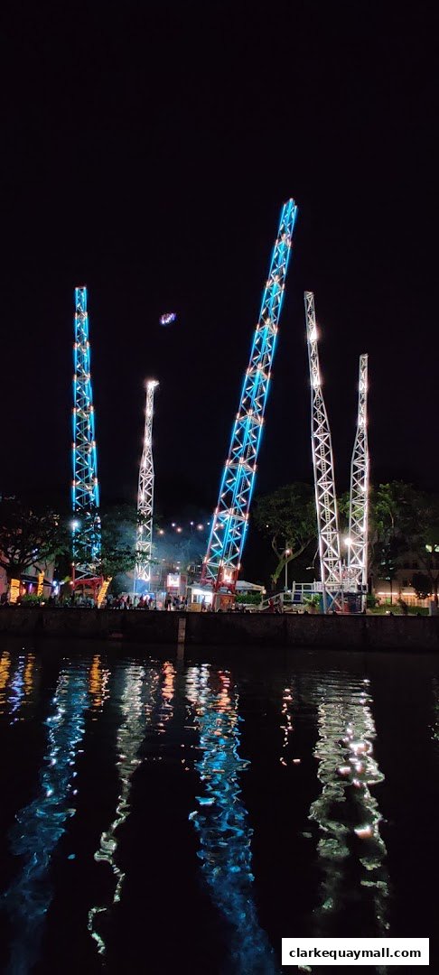 Night view of amusement rides with colorful lights reflecting on the water.