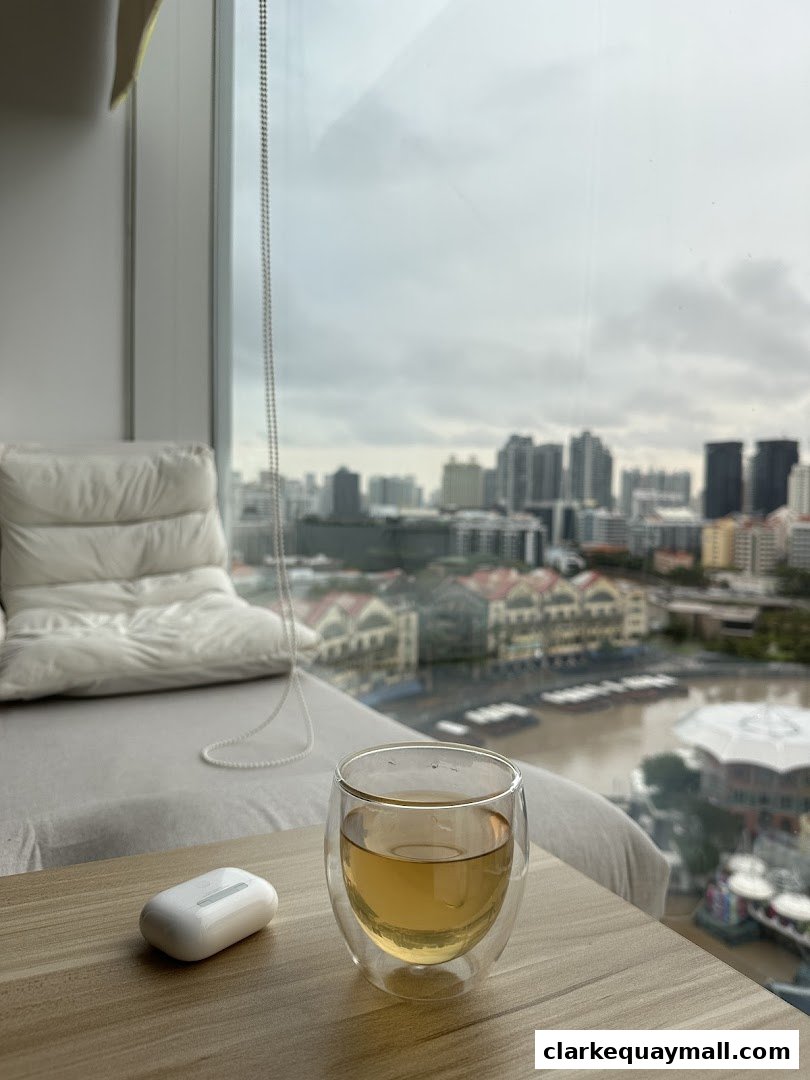 A glass of tea and earbuds sit on a table with a city view.