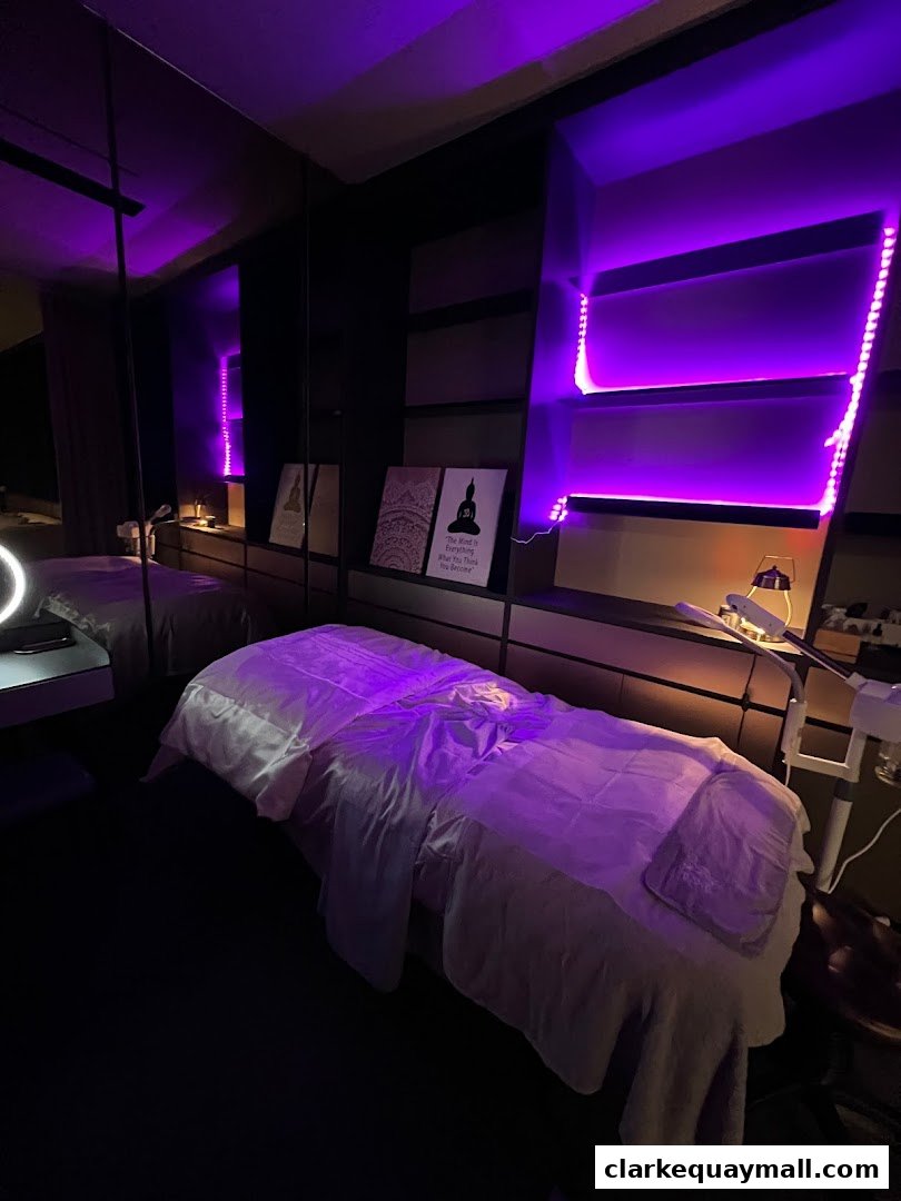 A treatment room with a massage bed, purple lighting, and inspirational wall art.