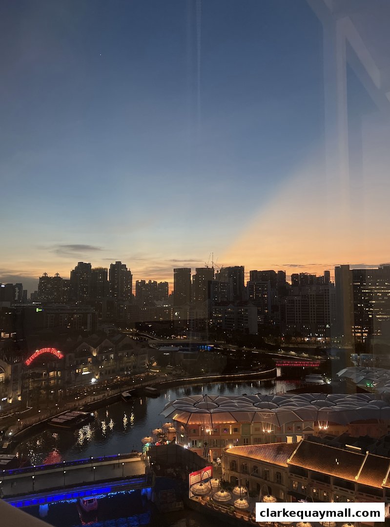 A city skyline at dusk with a river and illuminated buildings.