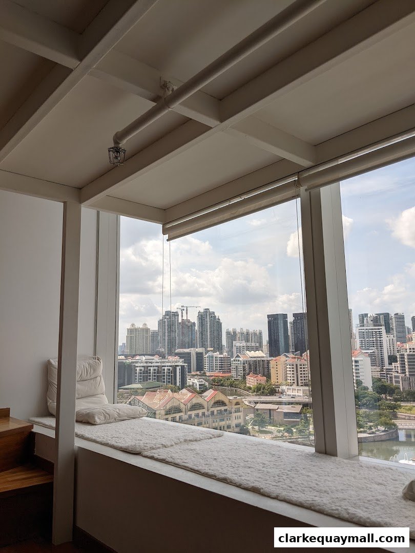 A cozy window seat with plush cushions offers a stunning panoramic view of a cityscape.