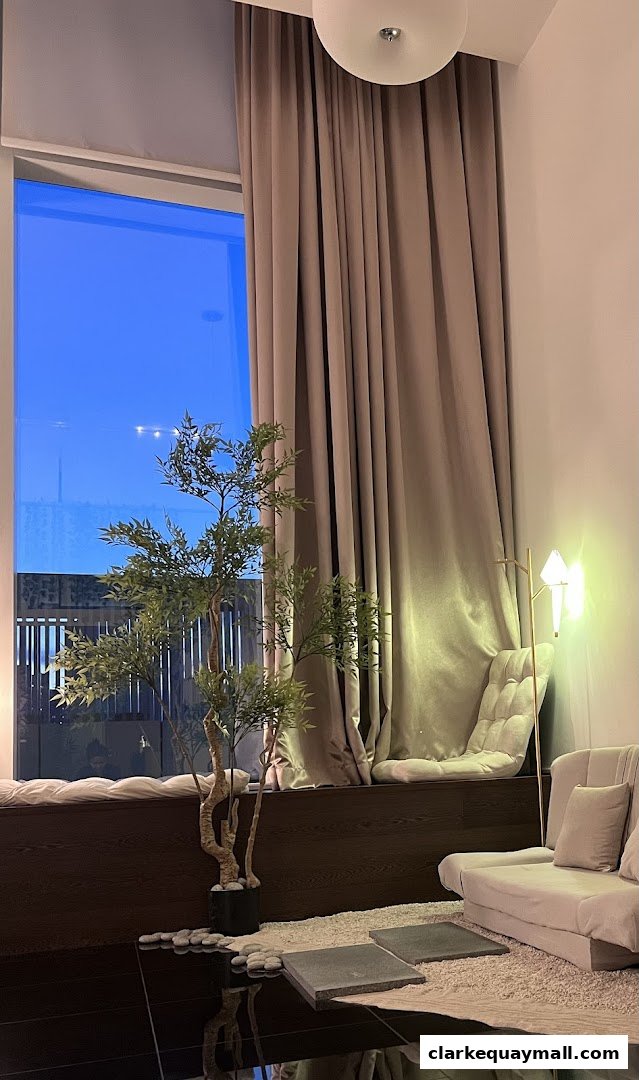 A cozy seating area with a large window, plush cushions, and a decorative tree.