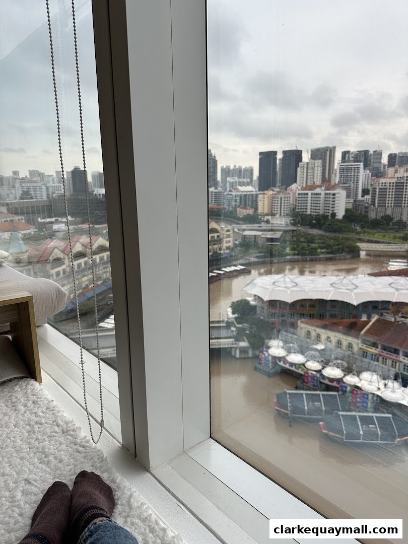View from a window overlooking a city skyline and river with boats.