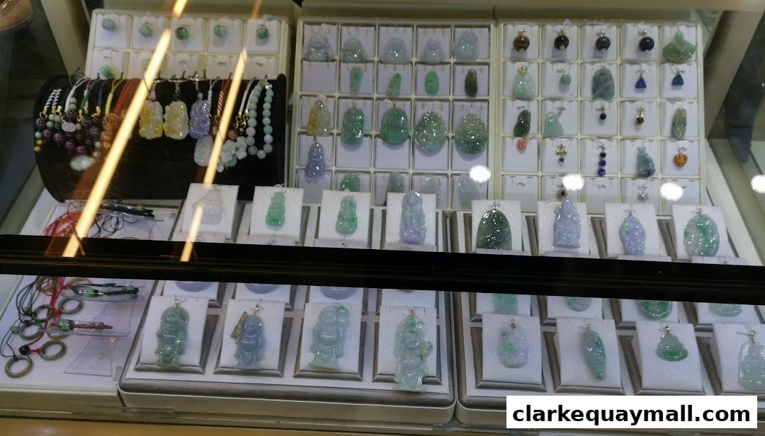 A display case filled with various jade pendants and bracelets, showcasing intricate carvings.