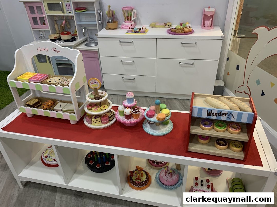 A display of toy bakery items including cakes, cookies, macarons, and bread.